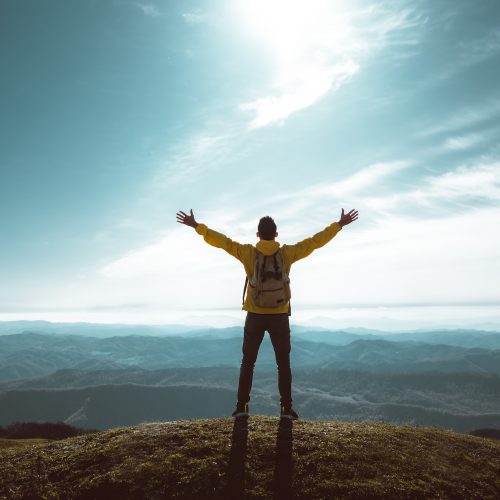 Hiker with arms up standing on the top of the mountain